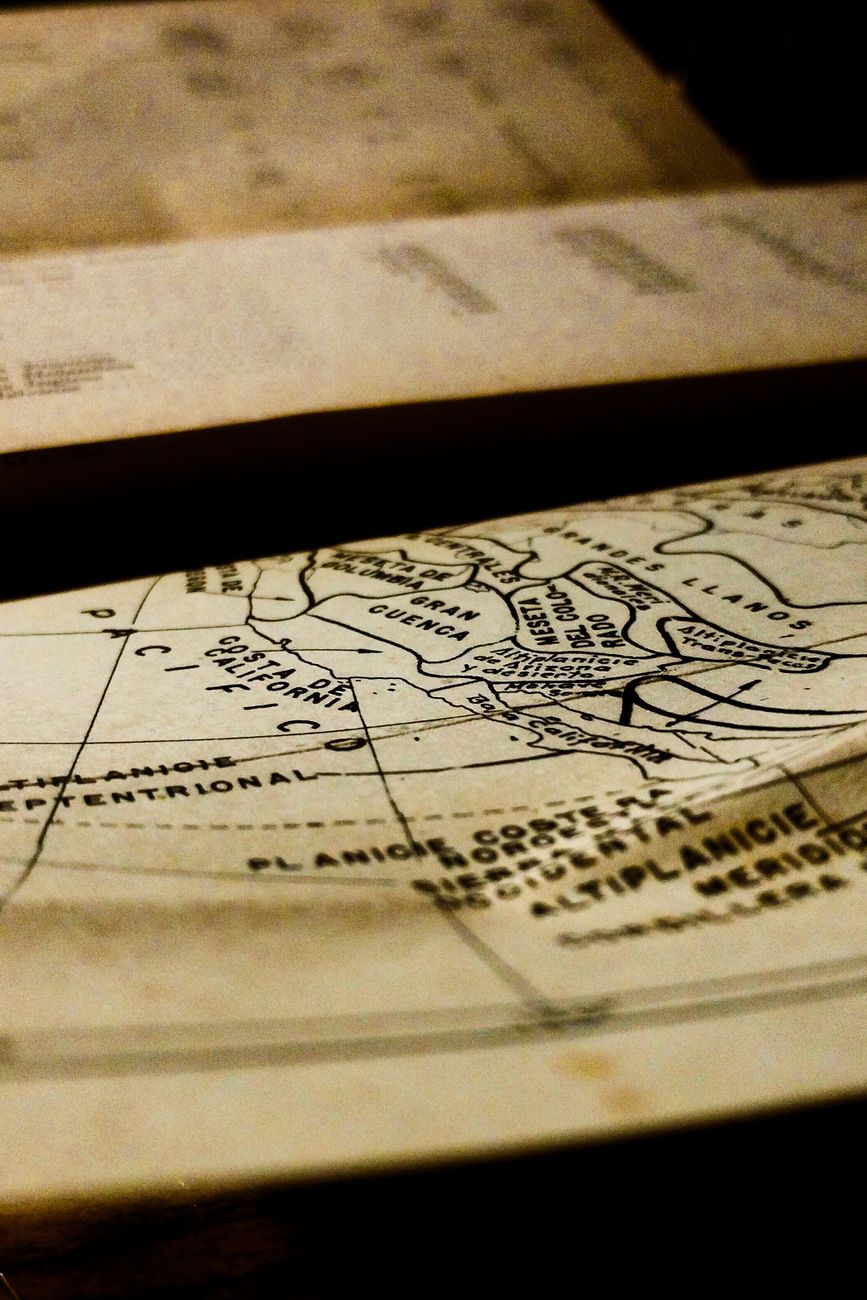 Travel writer reviewing topographic maps in timber lodge